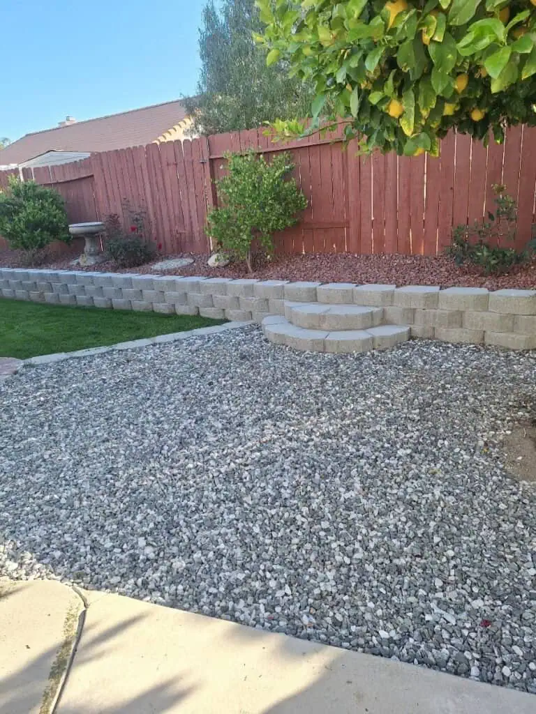 Garden landscape with stone steps and a red wooden fence in a backyard.