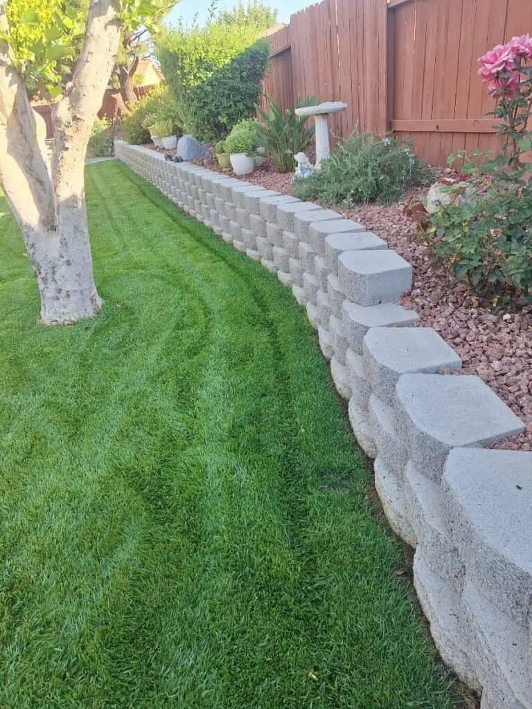 Retaining wall with gray concrete blocks in a landscaped garden setting.